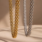 The Chunky Link Mesh Necklace, available in bold gold and silver tones, stands out as a statement piece against a neutral beige backdrop.