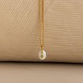 Close up of a Gold North Star Birthstone Necklace with a White Iridescent Opal Gemstone.