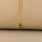 Close up of a Gold North Star Birthstone Necklace with a Green Peridot Gemstone.
