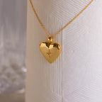 A gold heart-shaped locket with a north star CZ diamond in the center on a delicate cable chain.