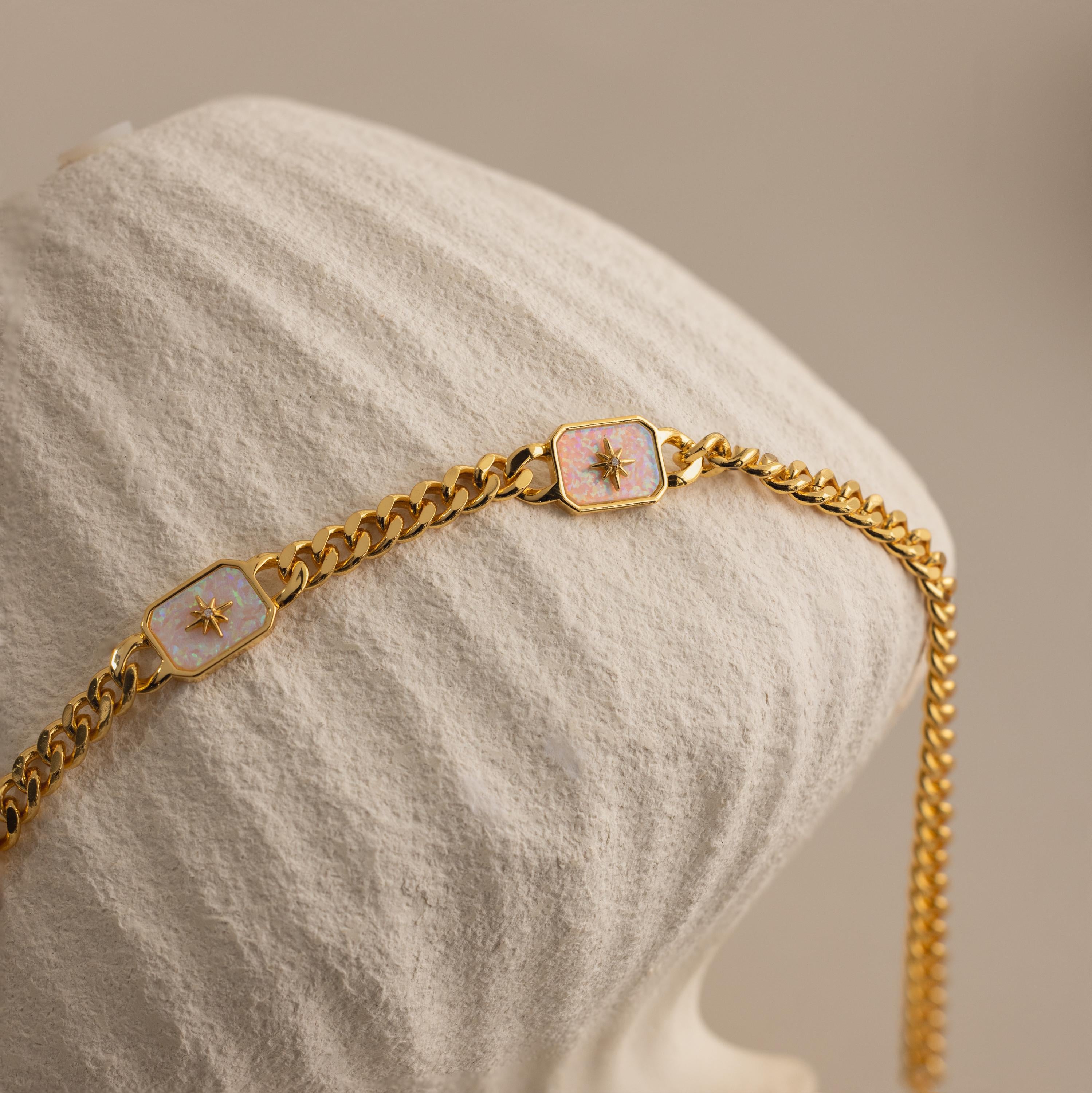 Close-up of Gold North Star Trio Opal Necklace draped over a textured cream vase.