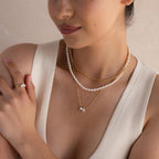 Woman wearing layered pearl and gold necklaces, including a Pearl Diamond Necklace with a teardrop diamond, a pearl ring, and a cream sleeveless top.