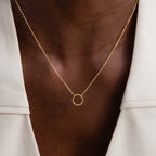 The Large Rolo Clasp Necklace, a bold gold chain with a circular pendant, is styled over a white blazer to bring a modern essential touch to any outfit.