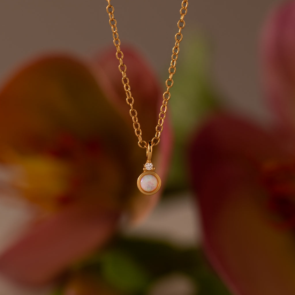 Image of our our Opal Diamond Necklace in Gold, against a floral background