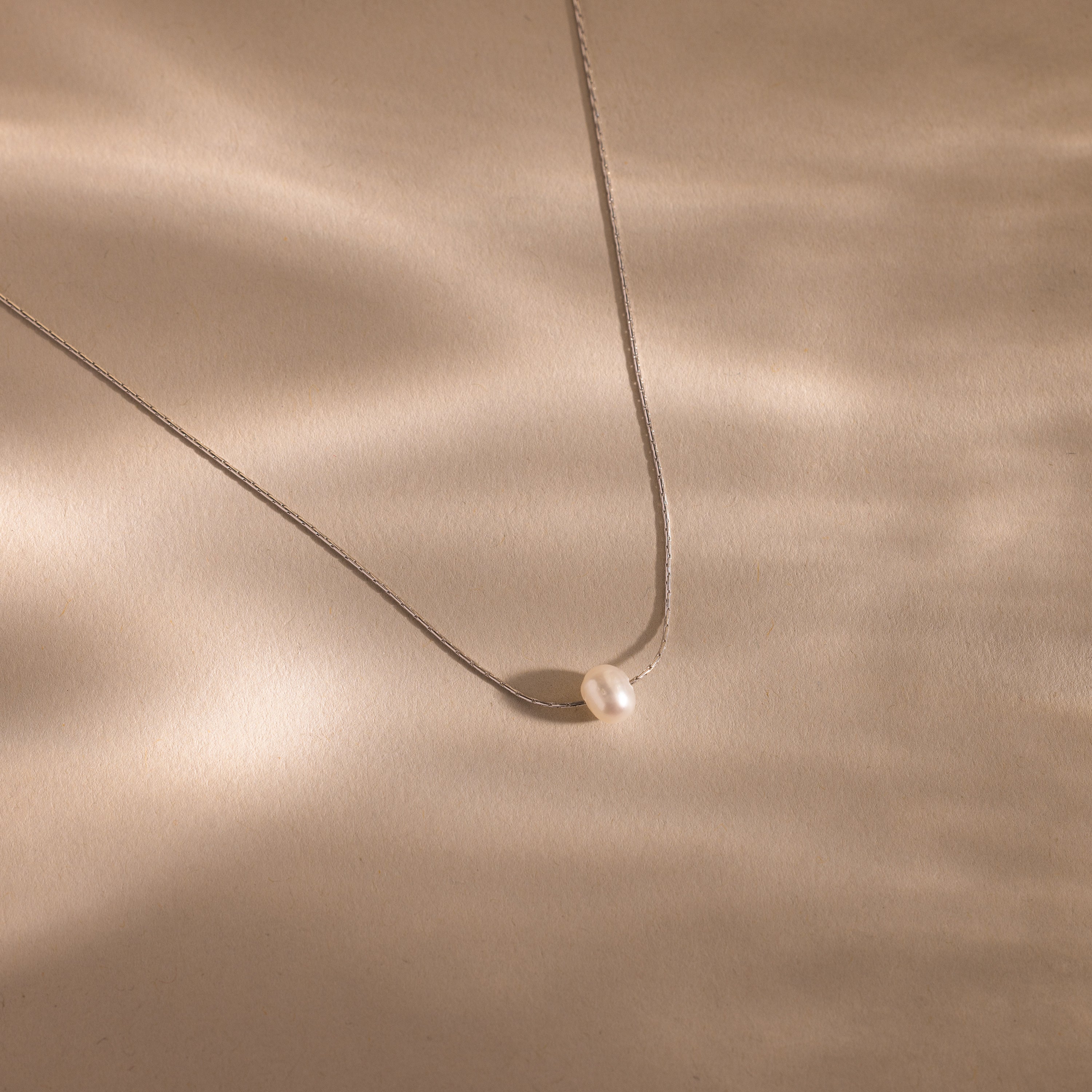 The Tiny Pearl Dot Necklace features a delicate chain with a classic pearl dot design, offering effortless elegance in a simple and timeless jewelry piece.