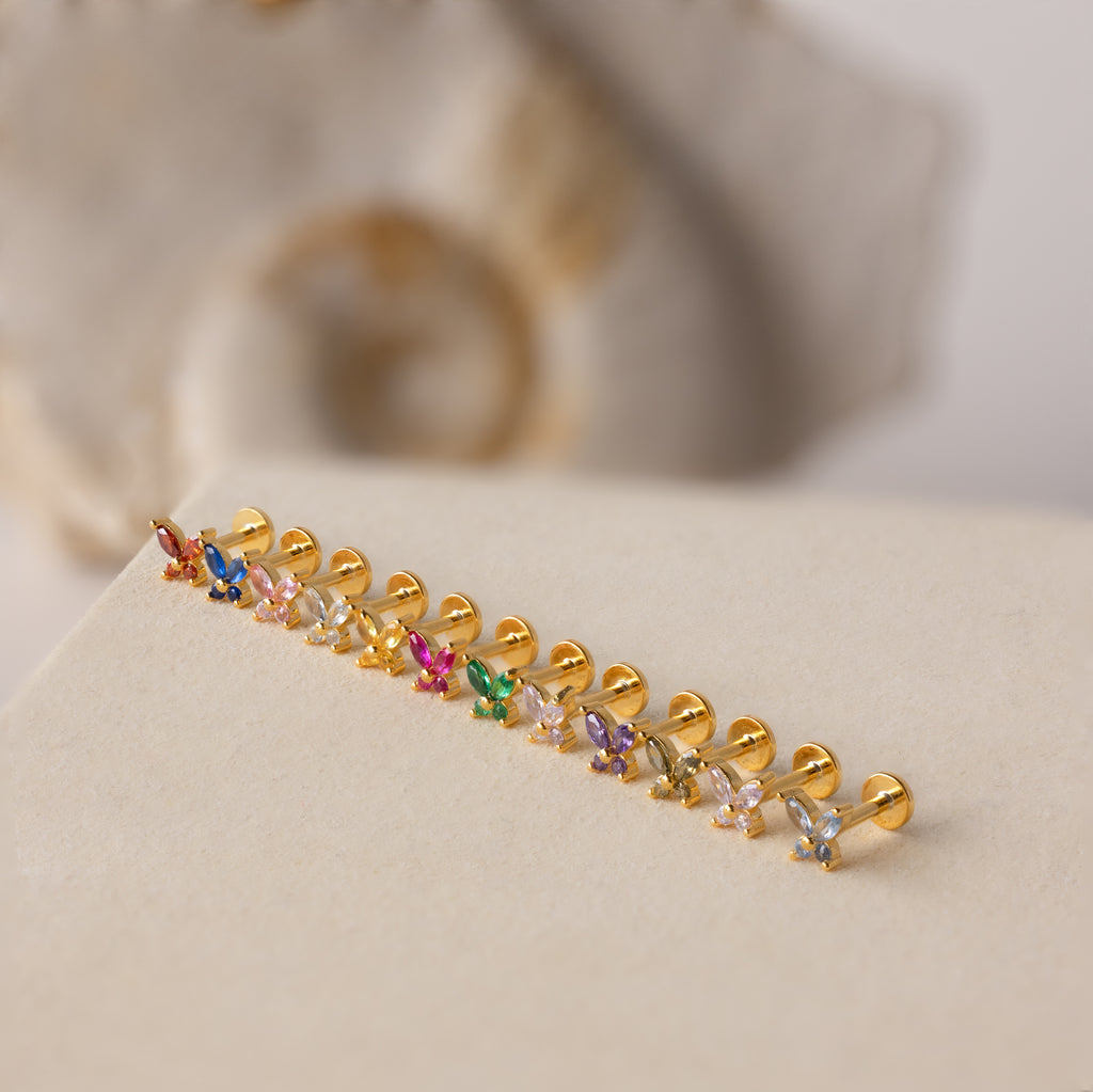 Butterfly Amethyst Flatback Studs with vibrant gemstones rest on a beige surface, ideal for anyone seeking unique, personalized jewelry.