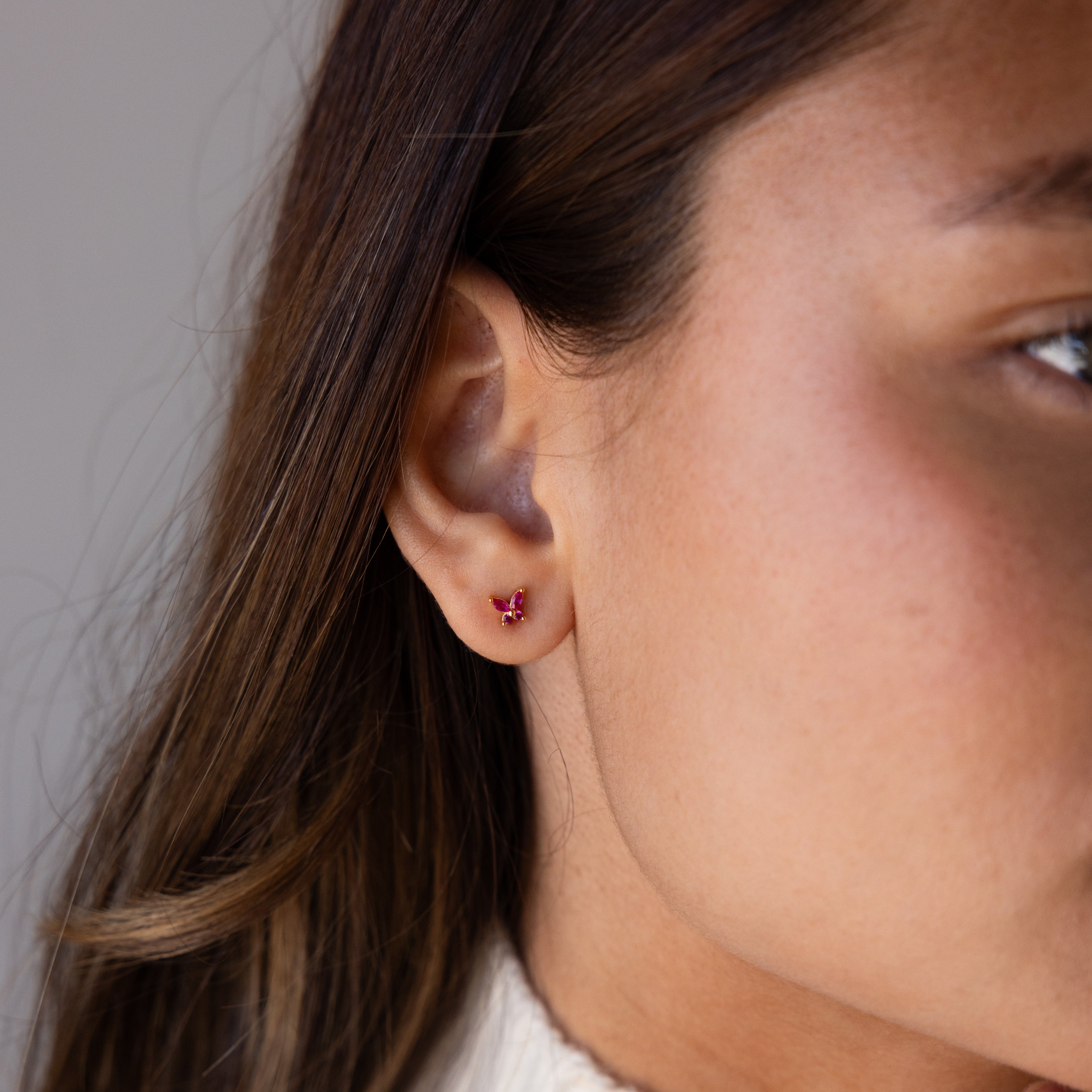 Close-up of a womans ear wearing a small Butterfly Amethyst Flatback Stud earring.