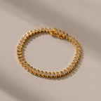 The S-Link Diamond Tennis Bracelet in 18K Gold, arranged in a circle on a sunlit, neutral surface, is an elegant jewelry piece with sparkling diamonds—perfect for any occasion.