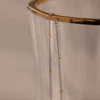 The Mixed Metal Beaded Necklace features a silver satellite chain with small gold beads, making it perfect for layering and adding an elegant touch to any outfit.