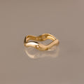 The Wavy Diamond Celestial Ring, featuring star-shaped engravings, is photographed on a reflective beige surface.