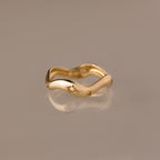 The Wavy Diamond Celestial Ring, featuring star-shaped engravings, is photographed on a reflective beige surface.
