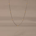 The Mixed Metal Beaded Necklace features a silver satellite chain with small gold beads evenly spaced—ideal for layering.
