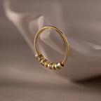 The Beaded Multiple Name Ring, featuring three engraved beads, is displayed on a white, curved ceramic surface.