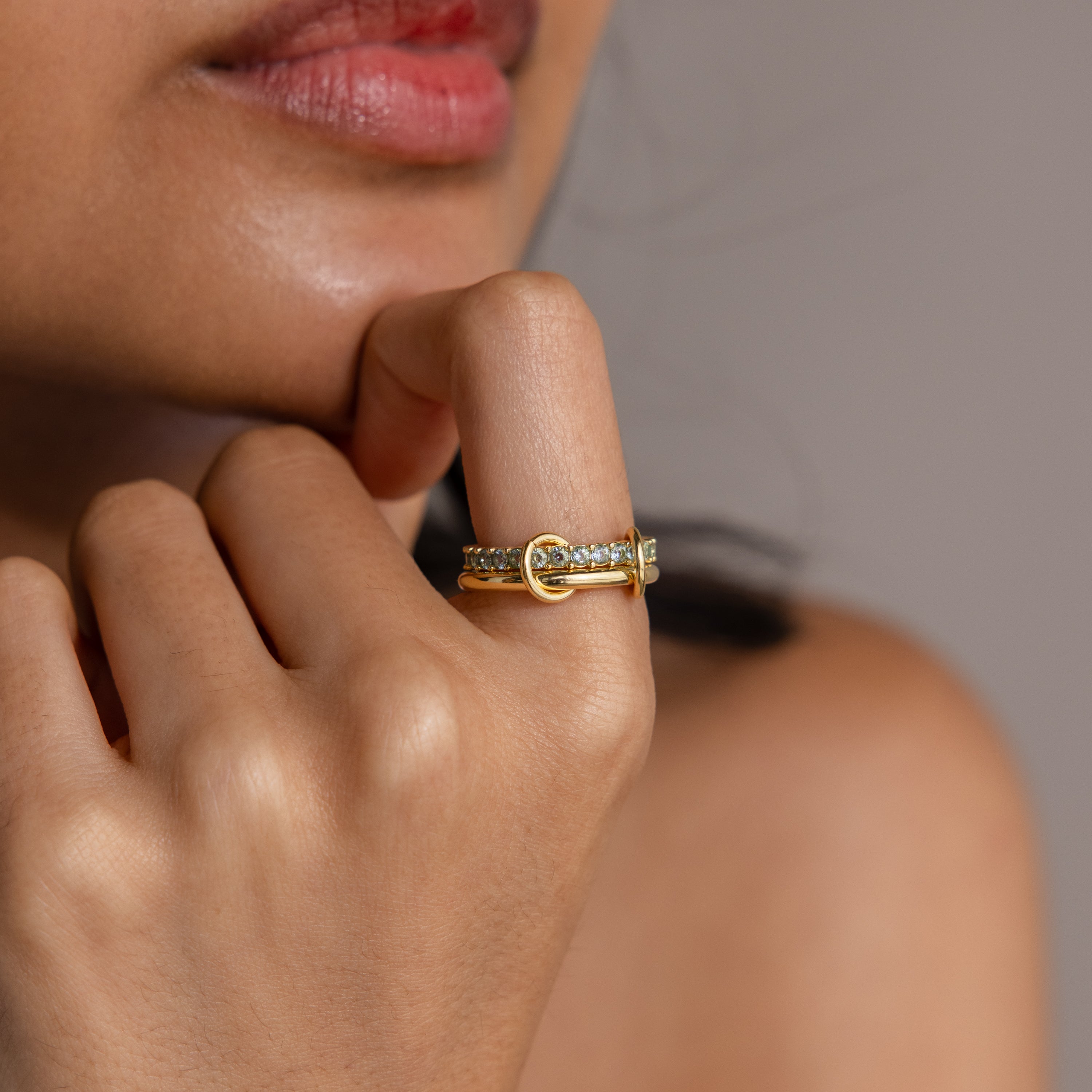 A woman’s hand with the Duo Aquamarine Tennis Linked Ring Set rests gently against her chin, the delicate bands sparkling with subtle elegance.