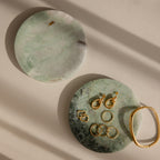 Two Green Marble Jewelry Dishes rest on a beige surface with soft shadows, one elegantly displaying gold jewelry.