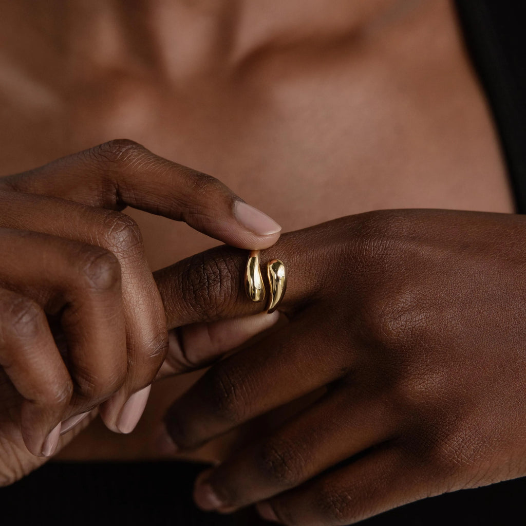 A hand wears the Duo Dome Ring—a bold gold piece with an open, adjustable design—against bare skin, ideal for statement jewelry lovers.