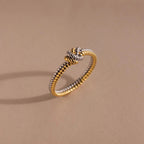 The Mixed Metal Knot Ring features a gold and silver twisted rope design with a knot, making it an ideal relationship gift. Shown on a beige background.