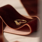 The Diamond Crescent Moon Ring is displayed on a folded piece of dark red velvet fabric.