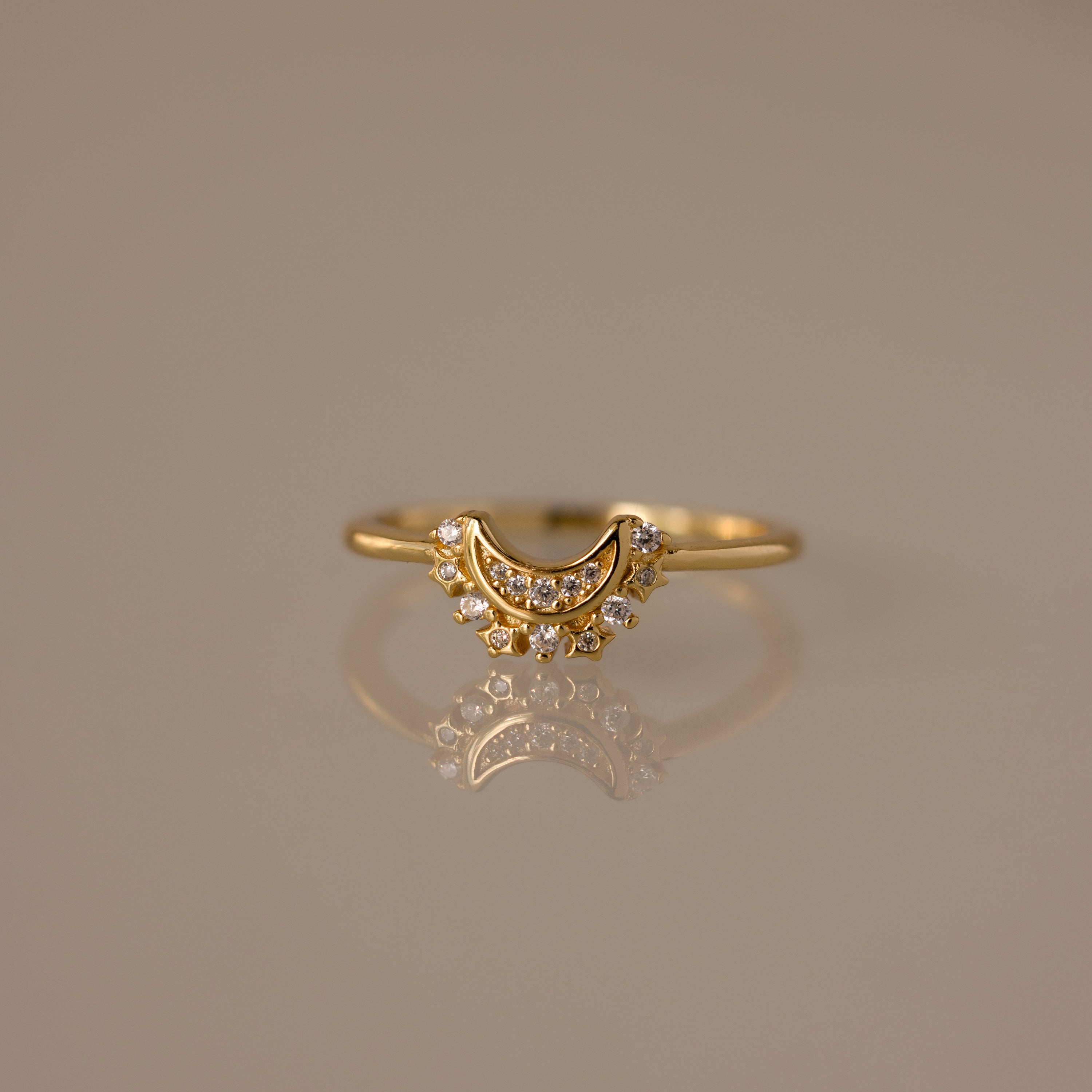 The Diamond Crescent Moon Ring features small sparkling stones and is displayed on a reflective surface—a celestial accessory perfect for adding shimmer to any look.