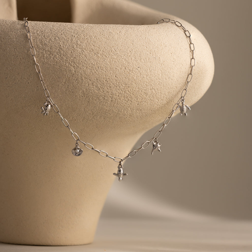 Seaside Charm Necklace in silver elegantly displayed on a smooth, light beige ceramic vase—ideal beach jewelry for summer.