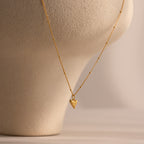 Shark Tooth Necklace displayed on a beige textured bust, perfect for adding coastal charm to your beachside look.