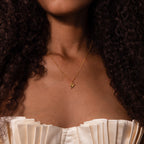 Woman wearing the Shark Tooth Necklace in 18K Gold, featuring an Africa-shaped pendant, paired with a cream pleated off-shoulder top.