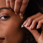 Close-up of a person holding a Dainty Shark Tooth Charm in Silver near their face, highlighting the beauty of coastal-inspired silver jewelry.