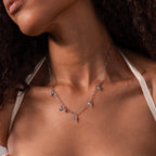 A woman wears the Seaside Charm Necklace in Silver, featuring various small pendants—ideal as summer beach jewelry.