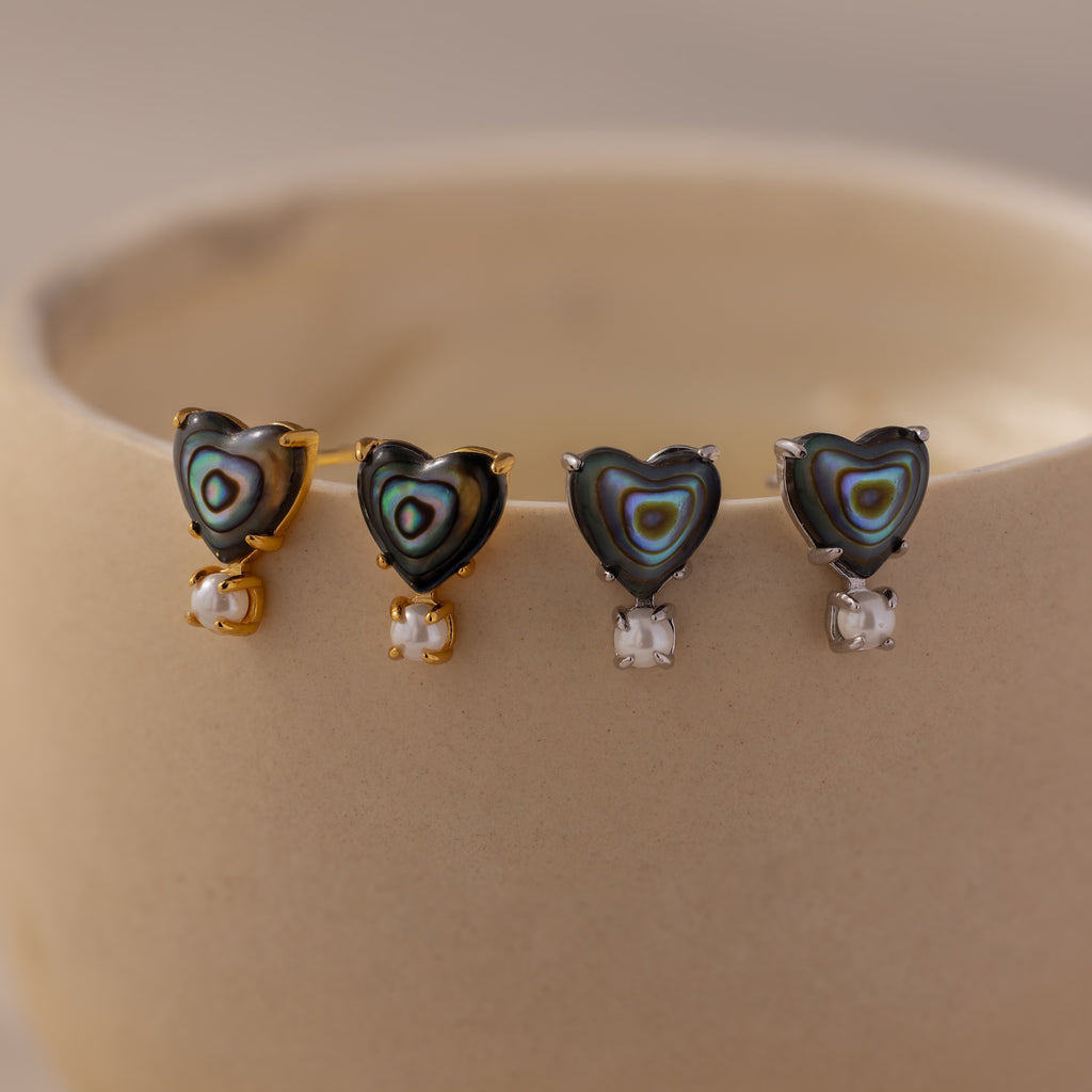 The Abalone Pearl Heart Studs feature heart-shaped designs with concentric patterns and small pearls, bringing coastal charm and elegance to your style.