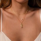 Woman wearing a white top and the Fish Pendant Necklace, paired with a two-pearl necklace for an elegant, ocean-inspired layered look.