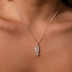 The Fish Pendant Necklace features a silver fish-shaped design, perfect for an ocean-inspired look or layering with your favorite jewelry.
