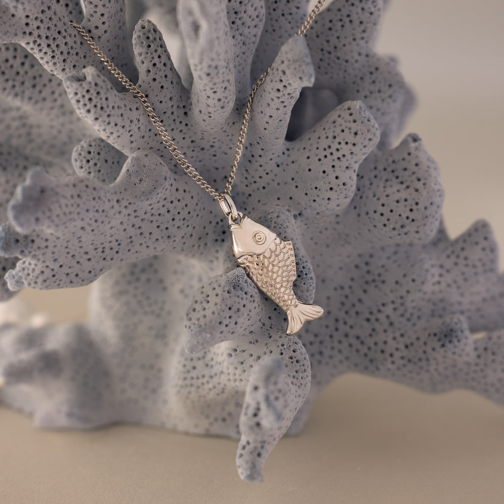 Fish Pendant Necklace shown on a textured light blue coral background—an elegant, ocean-inspired accessory ideal for everyday wear or as a unique layering piece.