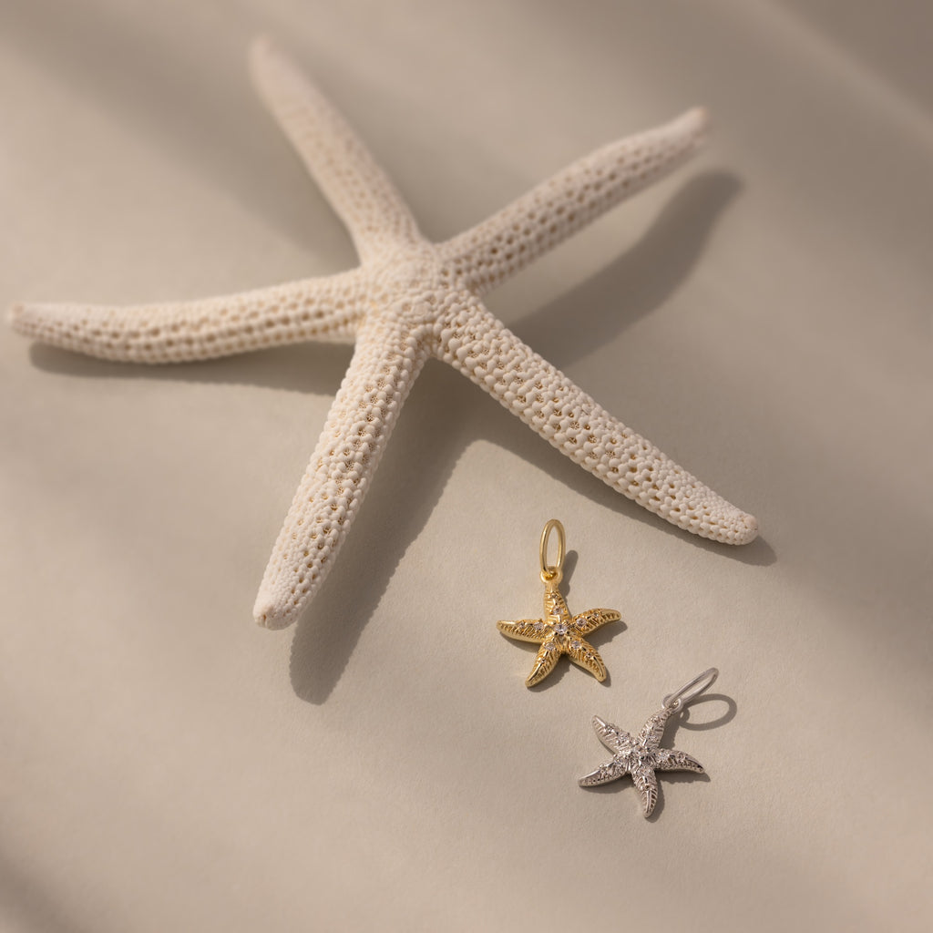 The Pave Starfish Charm in Silver shines on a soft beige background, adding coastal charm and elegance to your jewelry collection.