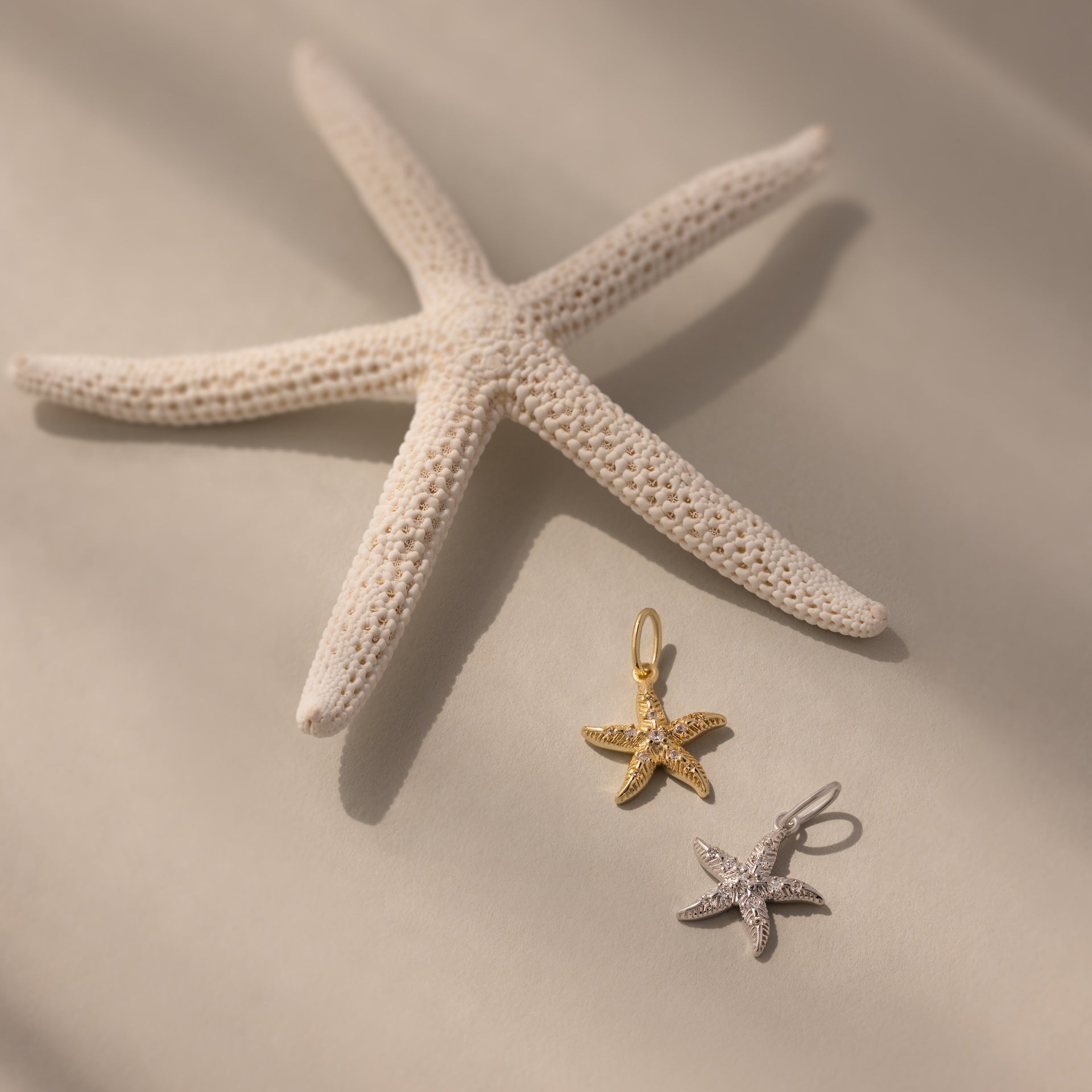 The Pave Starfish Charm in Silver shines on a soft beige background, adding coastal charm and elegance to your jewelry collection.