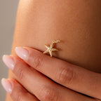 A manicured hand displays the Pave Starfish Charm in 18K Gold against bare skin, radiating coastal charm.