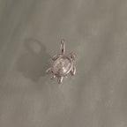 The Diamond Turtle Charm in Silver features a clear gemstone shell on a textured silver surface—an ideal piece for fans of ocean-inspired jewelry.