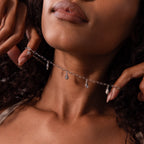 A woman wears the Ocean Charm Necklace, featuring delicate seaside-inspired charms around her neck.