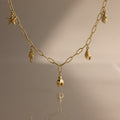 The Ocean Charm Necklace in 18K Gold features sea-themed charms—starfish, seahorse, shells, and pineapple—making it the perfect summer accessory on any neutral background.