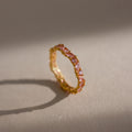 The Staggered Marquise Pink Tourmaline Ring features vibrant gemstones that cast a delicate shadow on a neutral surface.