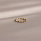 A delicate Dainty Marquise Birthstone Ring in Amethyst (February) rests on a soft beige surface, softly illuminated.