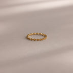 The Dainty Marquise Topaz Ring, featuring a repeating marquise pattern, rests on a smooth, neutral surface with soft shadows.