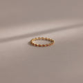 The Dainty Marquise Ruby Ring, featuring delicate gold and small red gemstones, is displayed on a soft, neutral background.