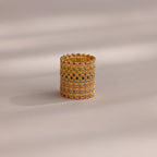 The Dainty Marquise Topaz Ring, featuring diamond-shaped patterns and multi-colored gemstones, is displayed upright alongside other gold rings on a neutral background with soft lighting.