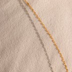 Up-close of a gold and silver mirror chain necklace, showcasing the reflective mirror design.