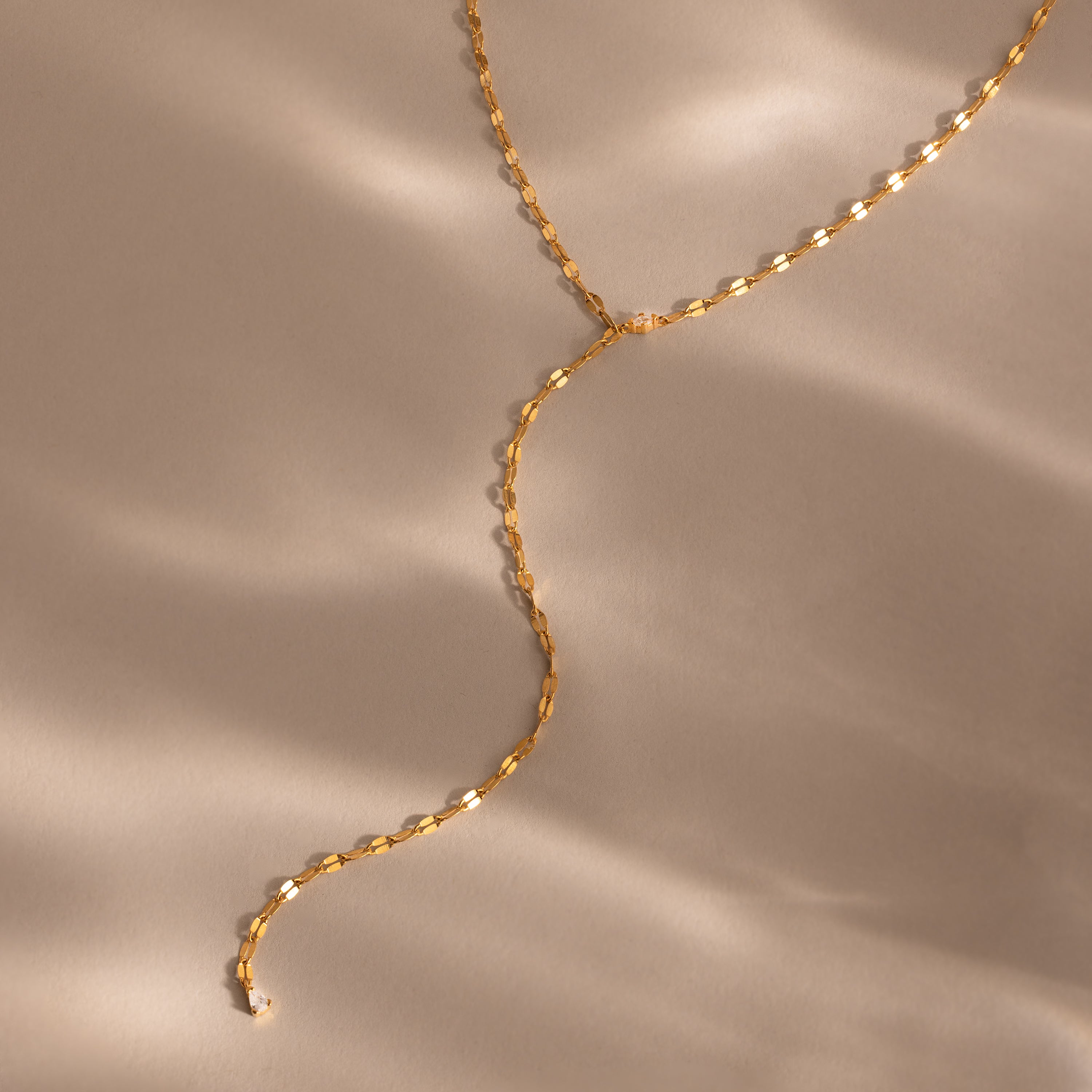 Gold dainty Sparkling Diamond Lariat Necklace with a delicate mirror chain design and two CZ diamond stones, displayed on a neutral surface.