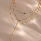 Close-up of a gold dainty Sparkling Layered Lariat Necklace, featuring 3 layers of mirror chain necklaces in varying lengths.