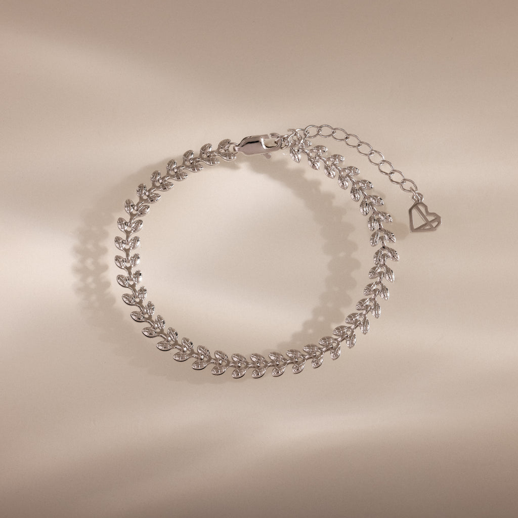 The Fishtail Chain Bracelet in Silver features an elegant leaf pattern with adjustable interwoven links and a heart-shaped charm—perfect as a stylish gift for any occasion.