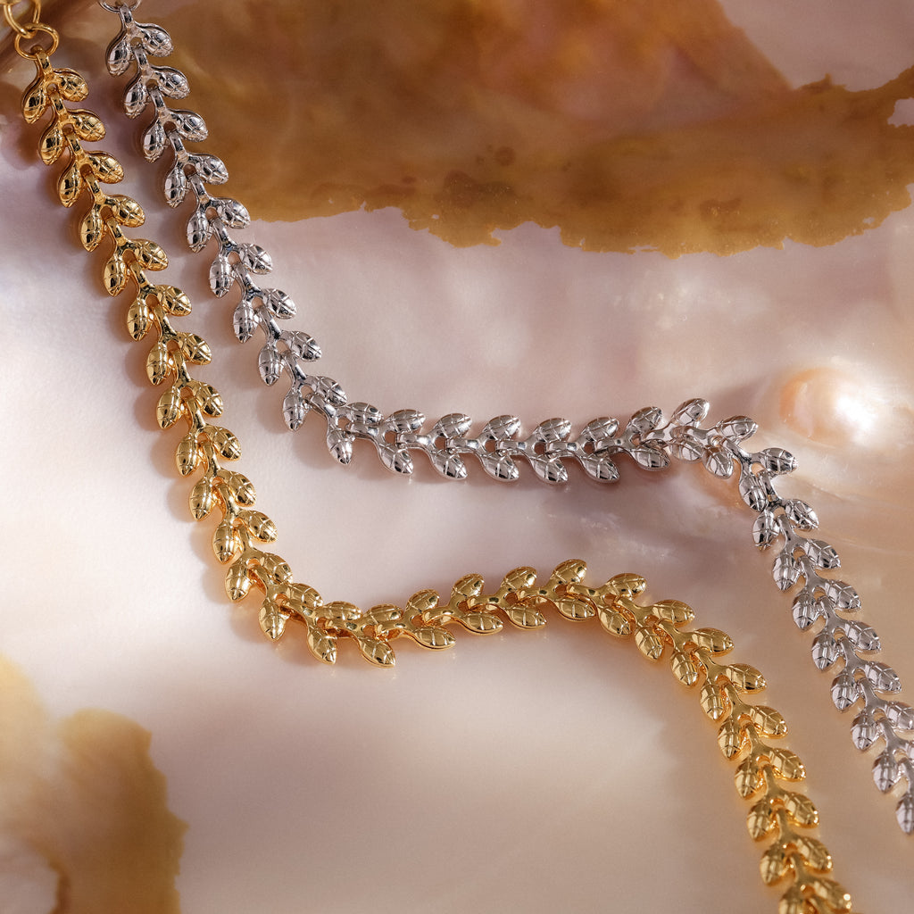 The Fishtail Chain Bracelet, featuring intricate craftsmanship and a cascading texture, is displayed on a marbled, pearlescent background.