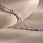 Close-up of the Dune Beaded Bracelet in Silver draped across a smooth, light stone surface, showcasing its polished silver beads.