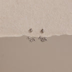 Starburst Cluster Ear Jackets in Sterling Silver, inspired by celestial jewelry, displayed on a textured cream and beige background.